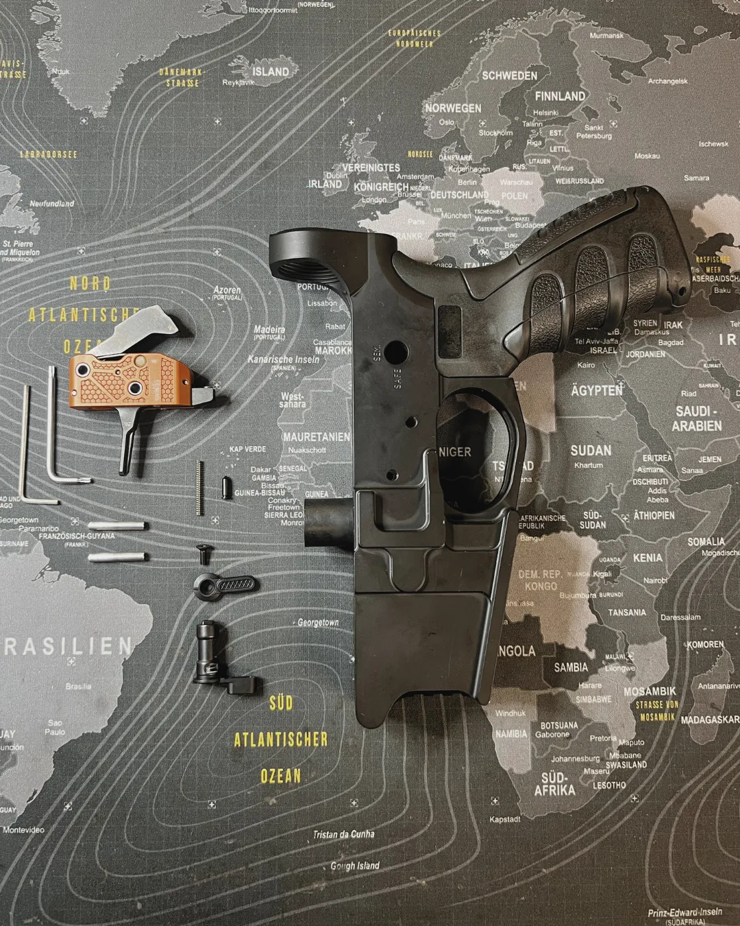 WPNTEC FENRIS Abzug Einbau – Lower Receiver mit Abzugsgruppe und Einzelteilen auf Weltkarte